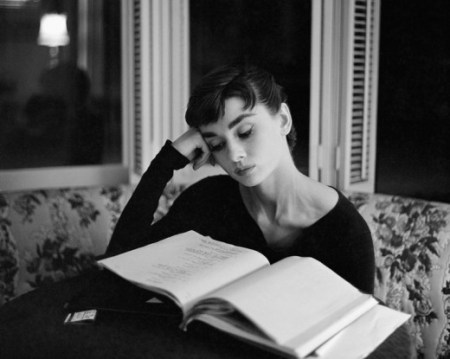 I think people like to post this picture and pretend it enhances Hepburn's aura of perfection –– "she reads!  she's smart!" –– but if you look closely, you'll see she's just perusing a script.